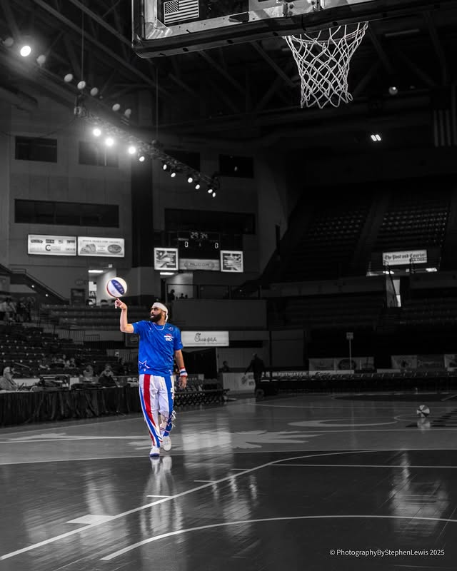 Lou Dunbar II spinning a ball in a black-and-white arena with blue color pop
